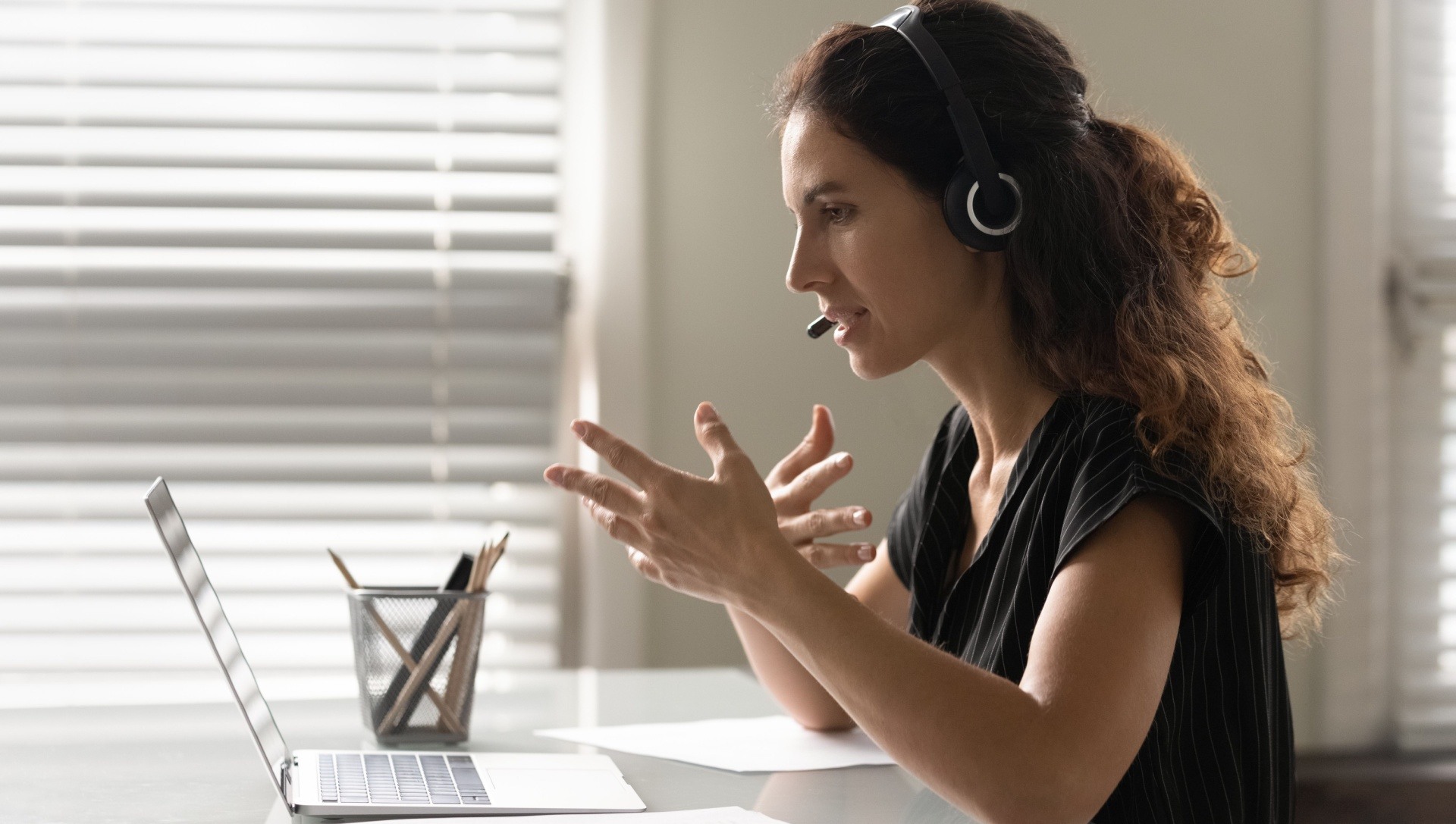 Woman on laptop speaking on a video call with a headset on 
