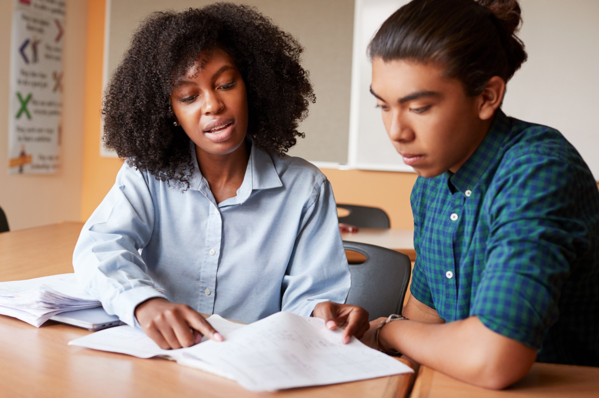 Woman wearing blue shirt tutoring a young man wearing a darker blue shirt