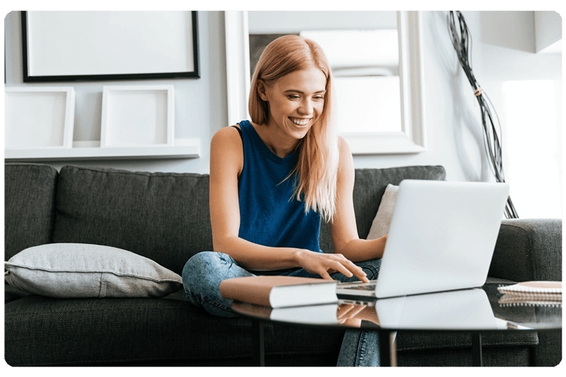 happy-woman-sitting-sofa-using-laptop-home-1-scaled