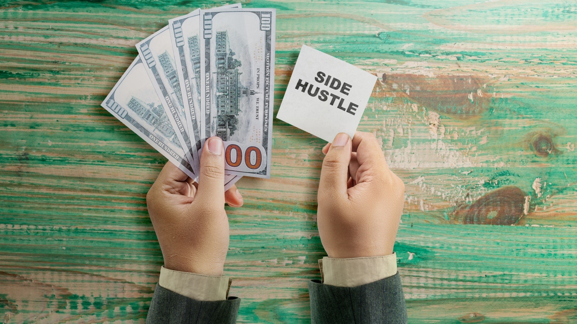 Man's hands holding money and some paper that says side hustle on it 