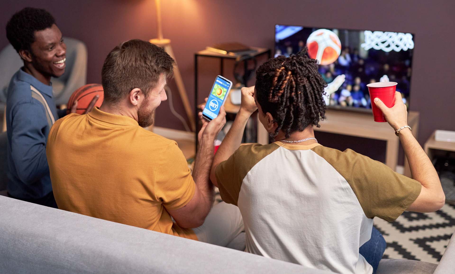 A group of three friends laughing and betting on a football game