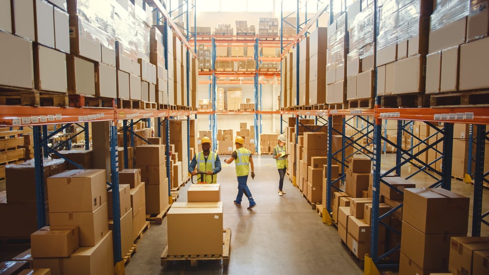 warehouse with stacked shelves and employees walking around