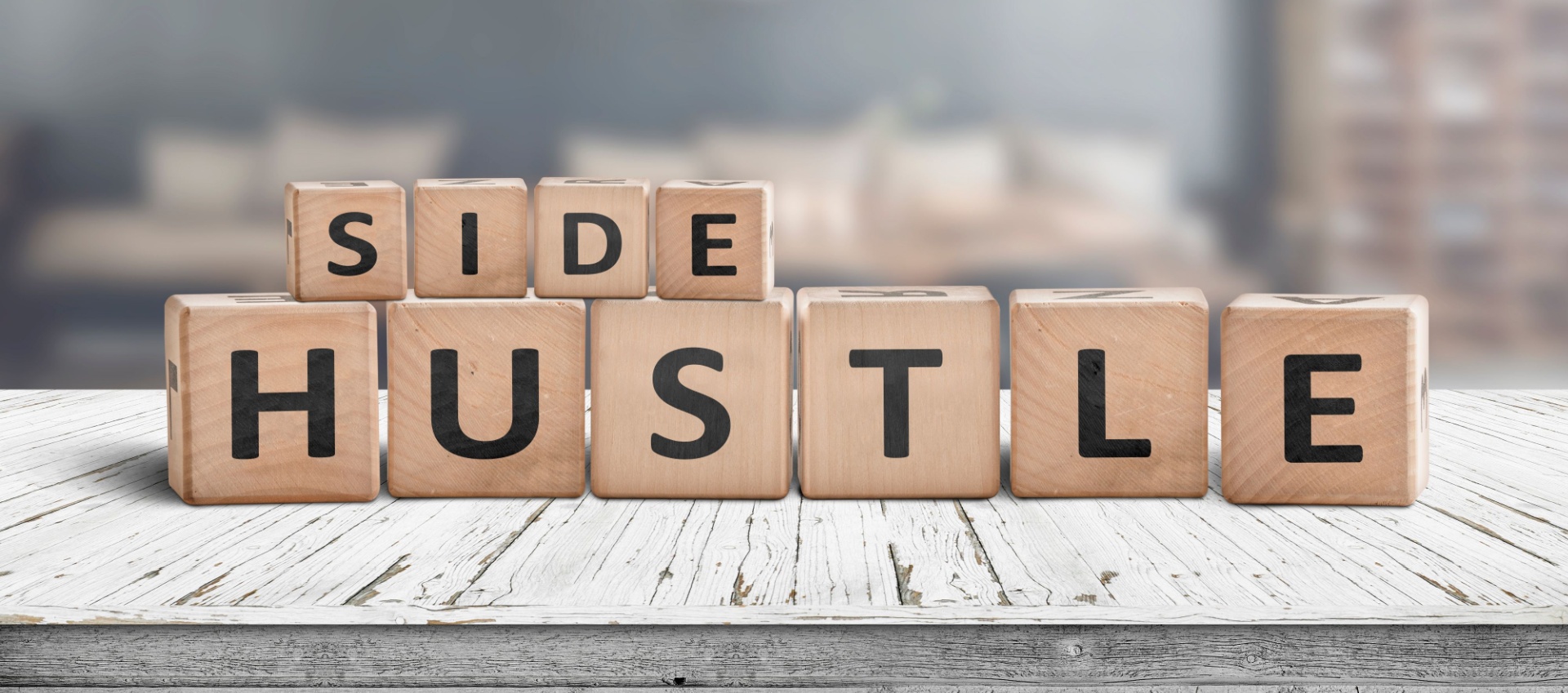 Side hustle in letter blocks on top of a wooden surface. 