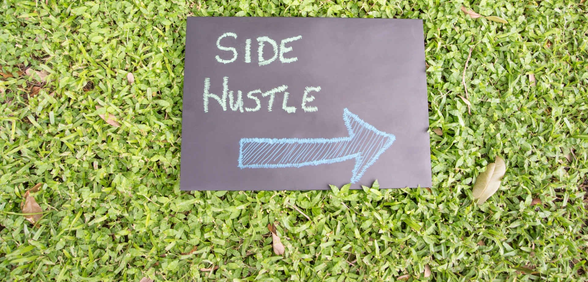 side hustle sign with an arrow on it in the grass
