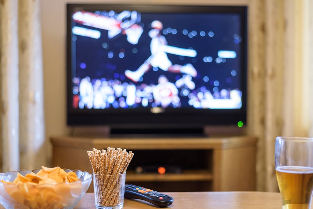 Snacks on a table in front a television with a basketball game